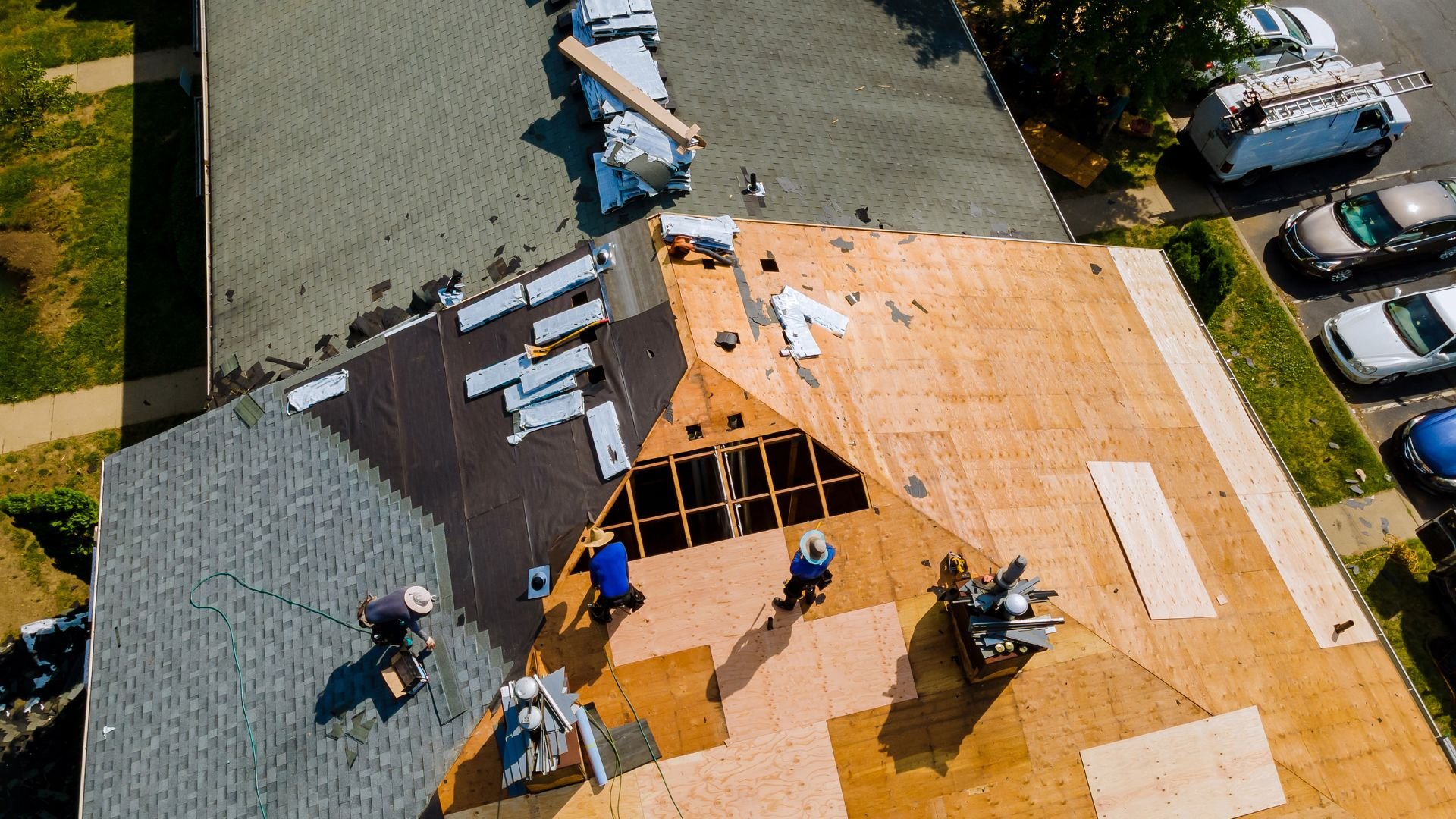 Aerial view of construction workers installing wooden roof shingles