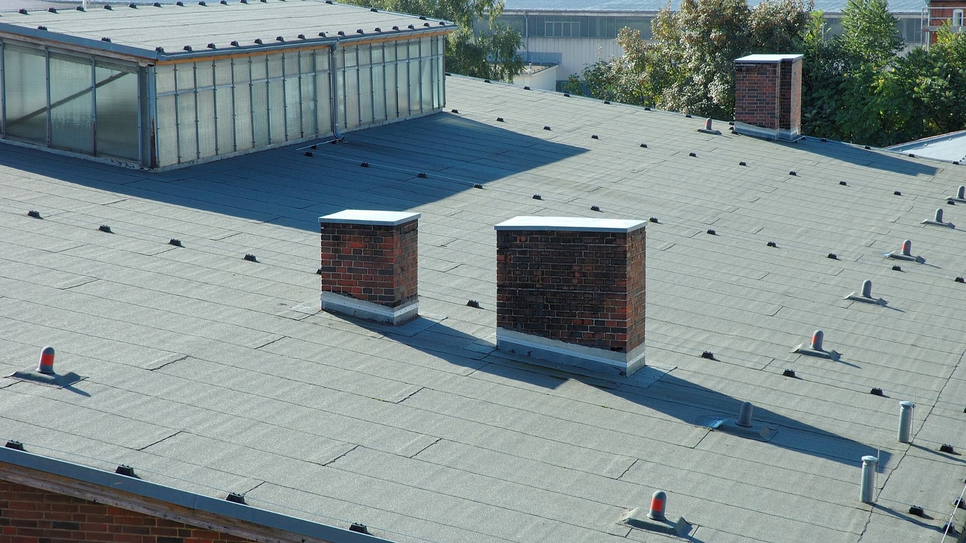 Aerial view of industrial flat roof with brick chimneys and safety markers