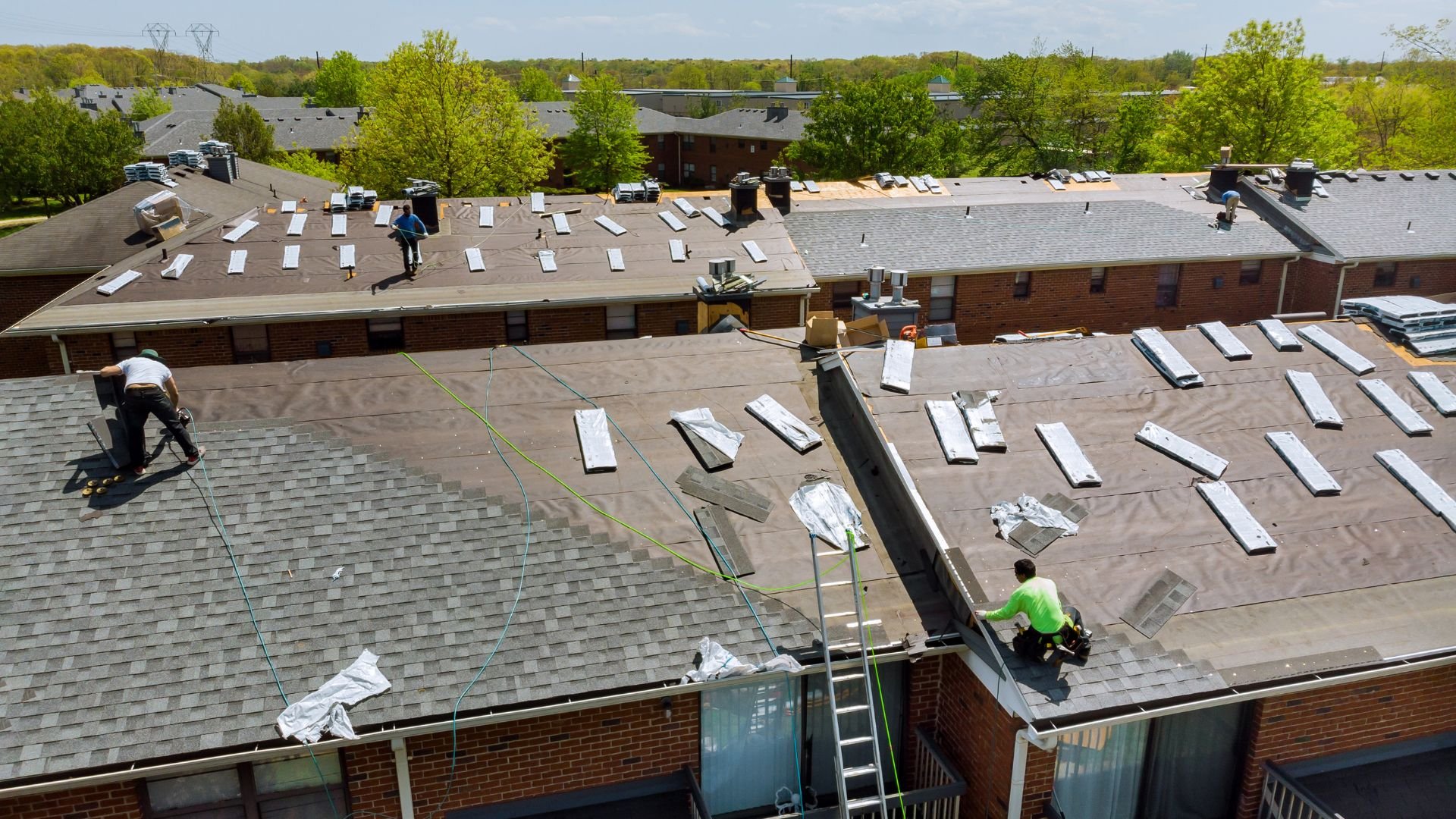 Workers installing solar panels on apartment building roofs on sunny day